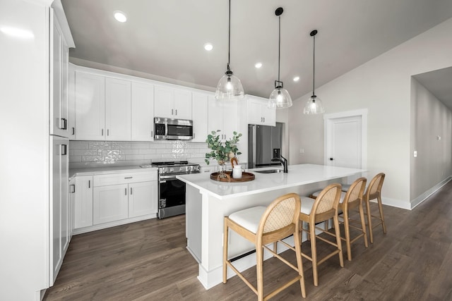 kitchen featuring recessed lighting, stainless steel appliances, backsplash, a sink, and a center island with sink
