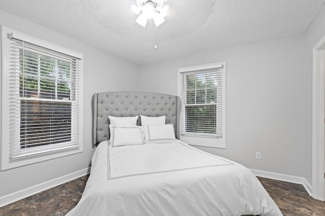 bedroom with a textured ceiling, baseboards, and multiple windows