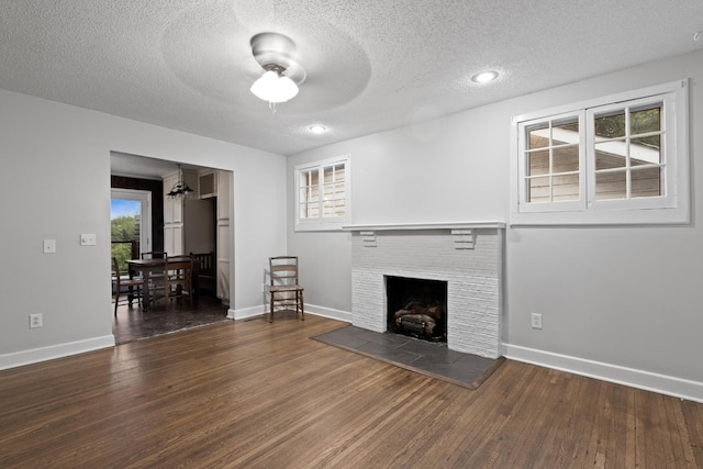 unfurnished living room with wood finished floors, ceiling fan, baseboards, and a textured ceiling
