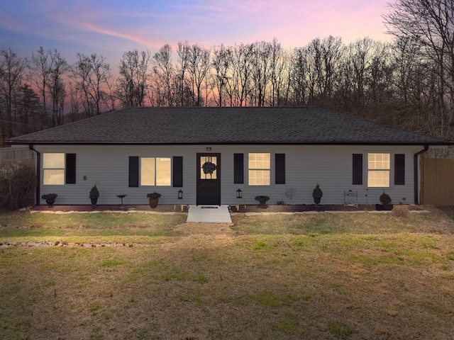 single story home featuring a shingled roof and a lawn