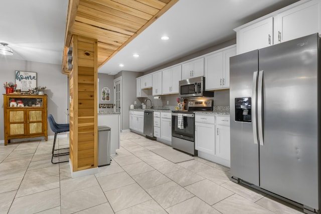 kitchen featuring recessed lighting, light stone countertops, white cabinets, and stainless steel appliances