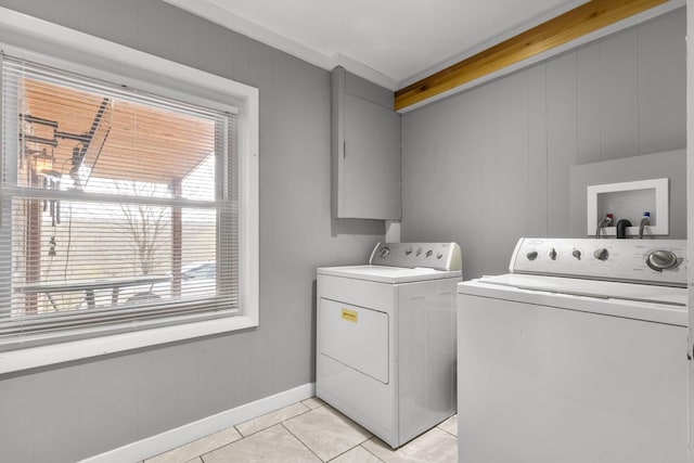 clothes washing area featuring light tile patterned flooring, washing machine and clothes dryer, laundry area, and baseboards