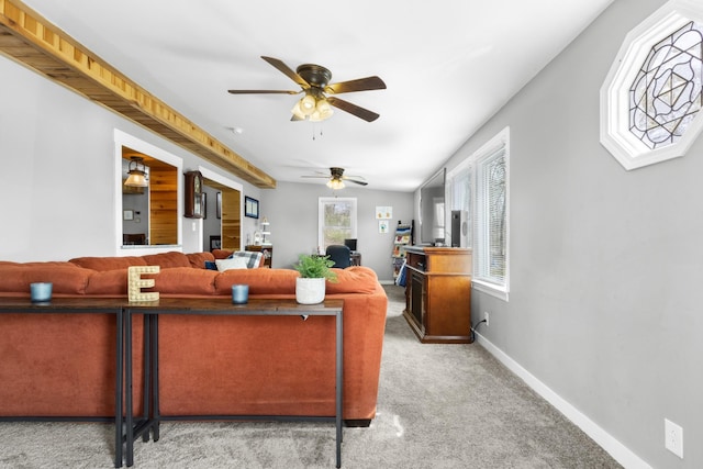 living room with a wealth of natural light, baseboards, ceiling fan, and light colored carpet