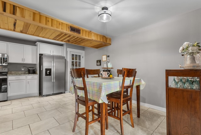dining space with light tile patterned flooring, visible vents, and baseboards