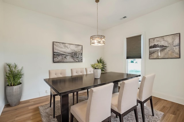 dining area featuring baseboards, visible vents, a notable chandelier, and light wood-style floors