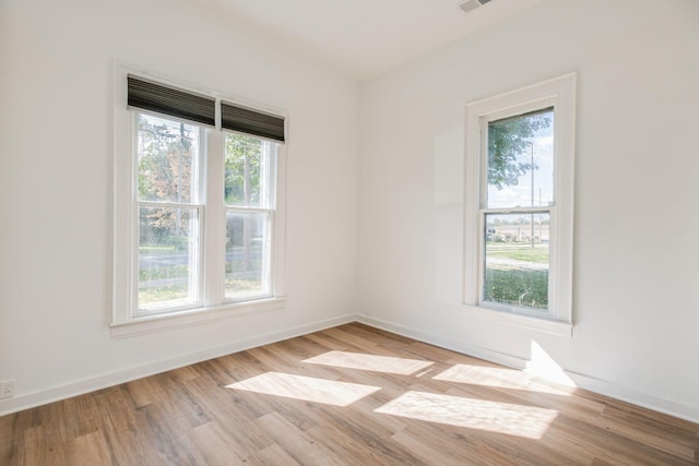 empty room with visible vents, wood finished floors, and baseboards