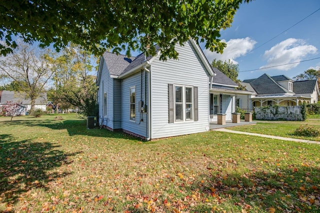 exterior space with a lawn, roof with shingles, and cooling unit
