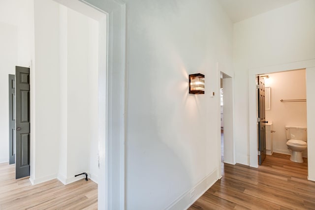 corridor with light wood-style floors and baseboards