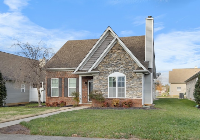 184 Whitman Aly, Clarksville, TN 37043 - view of front facade featuring a front yard, central AC unit, a chimney, stone siding, and roof with shingles