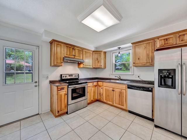 kitchen with a wealth of natural light, stainless steel appliances, dark countertops, and under cabinet range hood