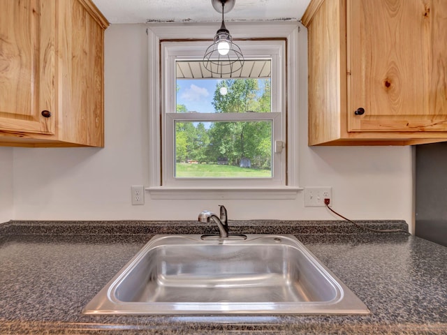 kitchen with dark countertops, light brown cabinets, and a sink