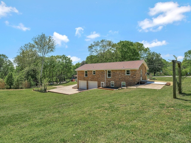 back of house featuring a lawn, driveway, brick siding, and an attached garage