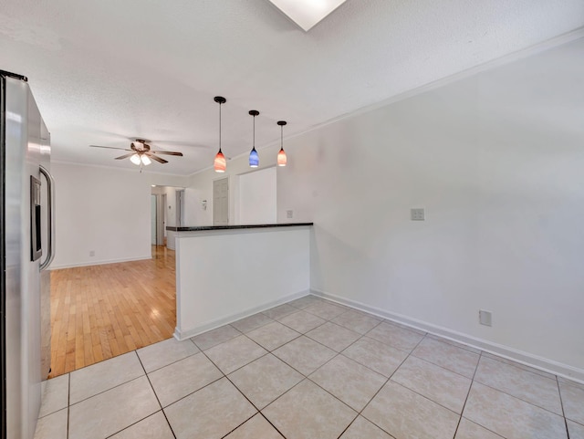 unfurnished room featuring light tile patterned flooring, a ceiling fan, baseboards, ornamental molding, and a textured ceiling