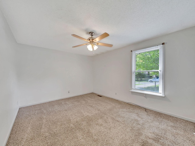 spare room with light colored carpet, a ceiling fan, and baseboards
