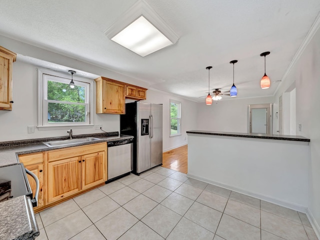 kitchen featuring dark countertops, a sink, stainless steel appliances, and pendant lighting