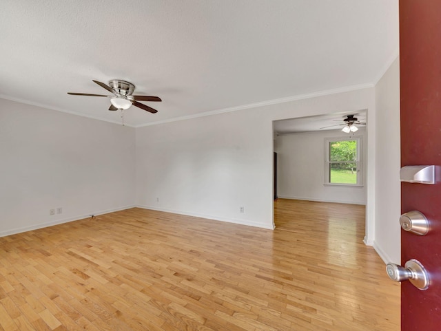 spare room with ornamental molding, a ceiling fan, baseboards, and light wood-style floors