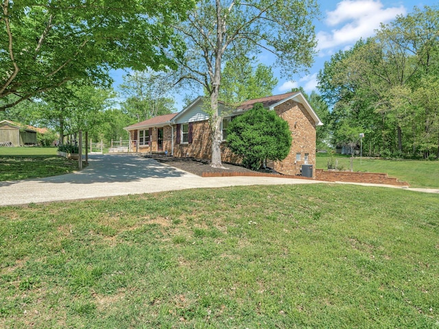 single story home featuring central AC unit, brick siding, and a front lawn
