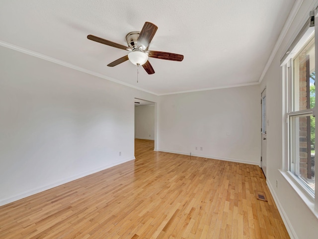 spare room with light wood finished floors, a ceiling fan, visible vents, and plenty of natural light
