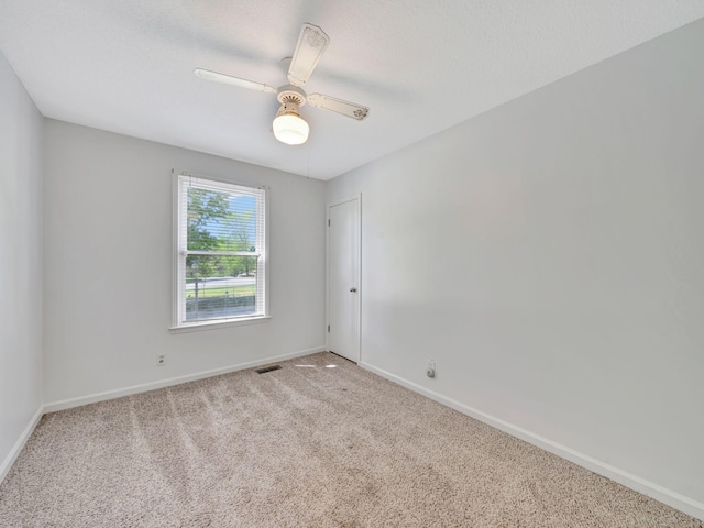 carpeted empty room with baseboards, visible vents, and ceiling fan