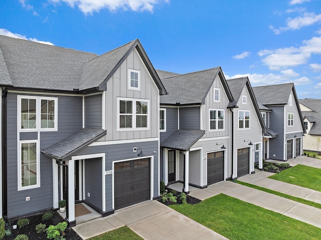 townhome / multi-family property with a residential view, driveway, an attached garage, and board and batten siding