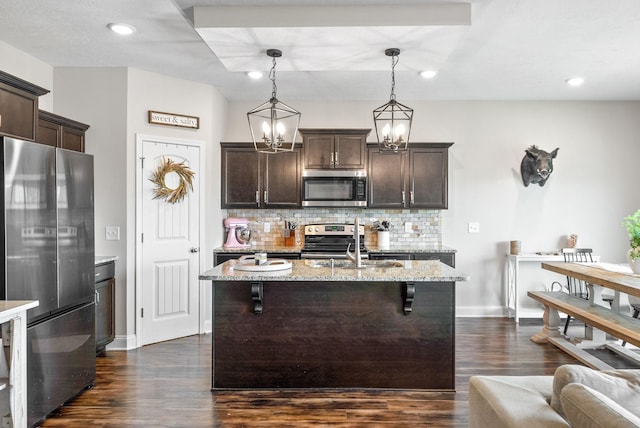 kitchen with dark brown cabinetry, appliances with stainless steel finishes, decorative backsplash, and a sink