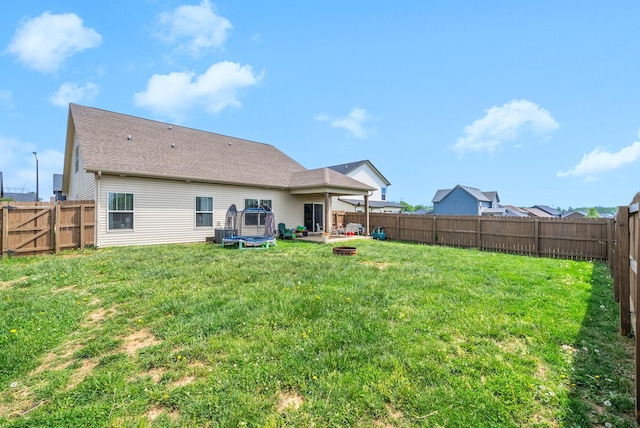 rear view of property with a yard, a fenced backyard, and an outdoor fire pit