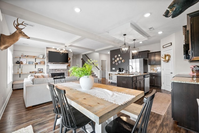 dining area featuring a stone fireplace, baseboards, a chandelier, recessed lighting, and dark wood-type flooring