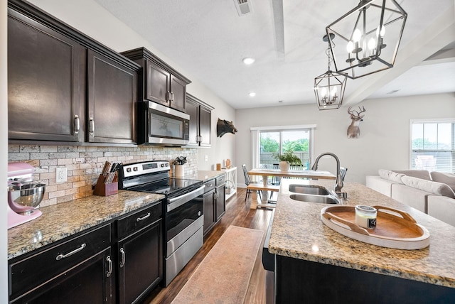 kitchen with dark wood-style flooring, appliances with stainless steel finishes, a sink, a chandelier, and plenty of natural light