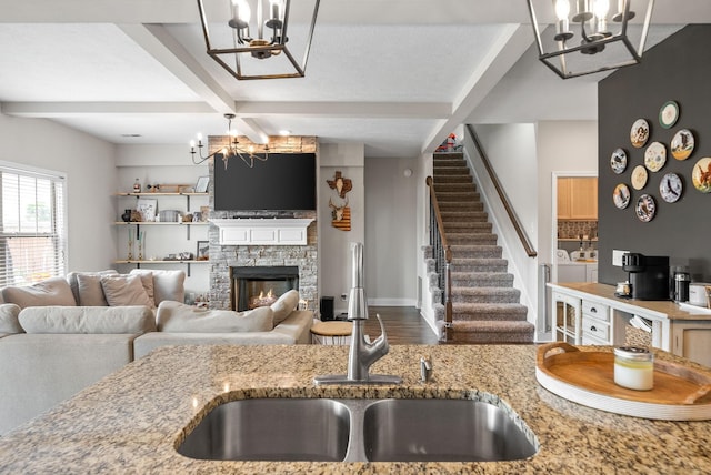kitchen featuring a sink, light stone counters, independent washer and dryer, and a notable chandelier