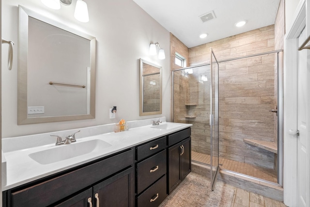 full bathroom featuring a sink, a stall shower, double vanity, and visible vents