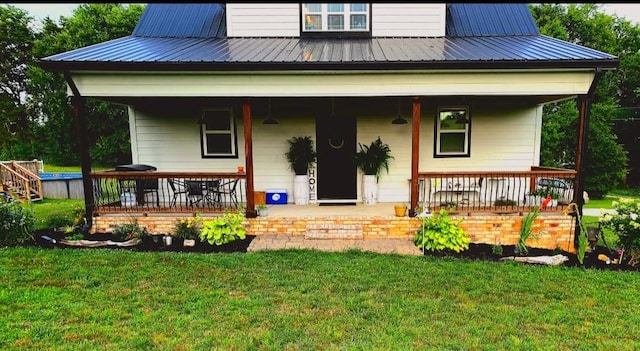 rear view of house featuring covered porch, metal roof, and a lawn