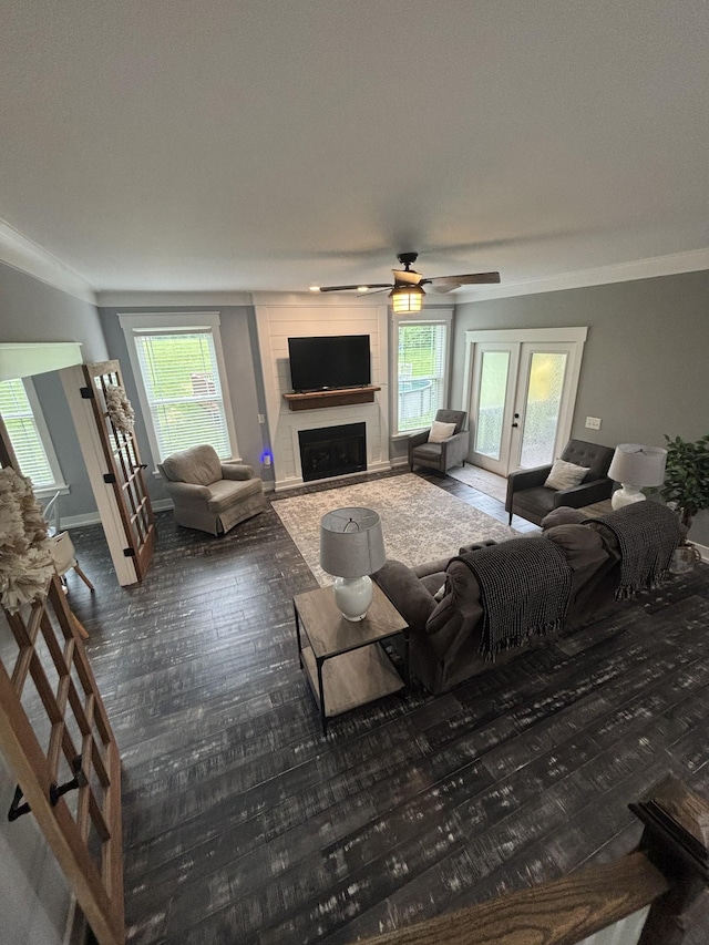 living room with a ceiling fan, healthy amount of natural light, a fireplace, ornamental molding, and baseboards
