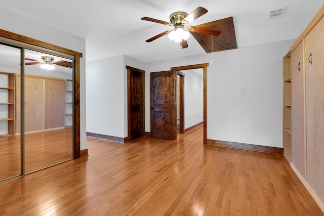 unfurnished bedroom featuring a closet, ceiling fan, light wood finished floors, baseboards, and visible vents