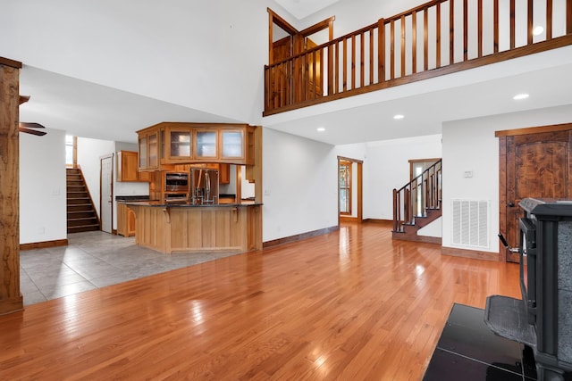 living area featuring a high ceiling, stairs, visible vents, and light wood-style flooring