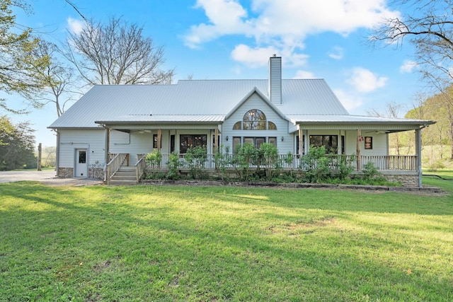 back of property featuring metal roof, a yard, covered porch, and a chimney