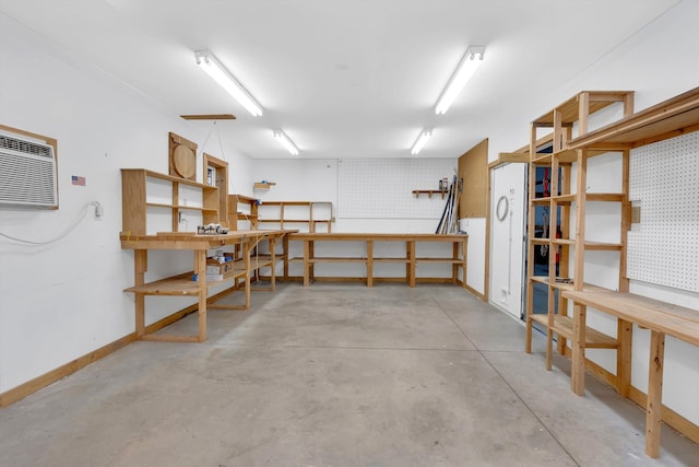 garage featuring a workshop area, baseboards, and a wall mounted AC