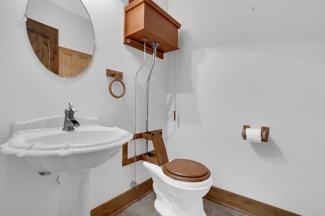 bathroom featuring baseboards, wood finished floors, and toilet
