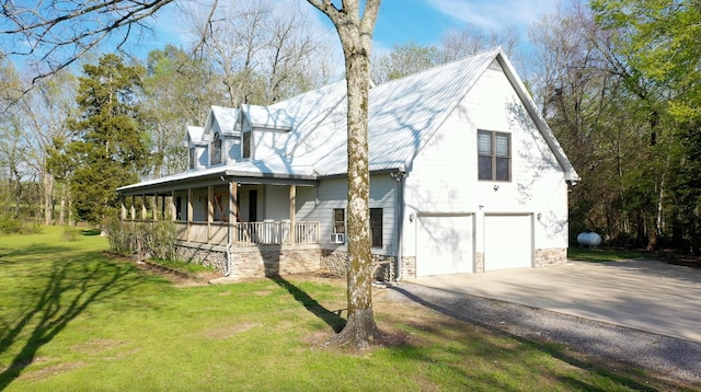 view of side of home featuring a porch, a yard, driveway, stone siding, and an attached garage