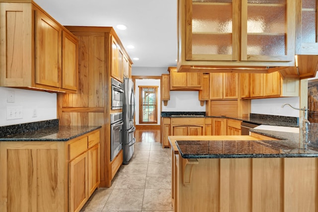 kitchen featuring dark stone counters, recessed lighting, a sink, stainless steel appliances, and a peninsula