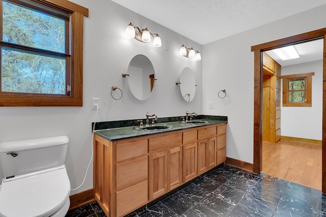 bathroom with baseboards, toilet, and a sink