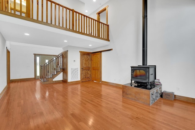 unfurnished living room featuring visible vents, recessed lighting, a towering ceiling, wood finished floors, and stairs