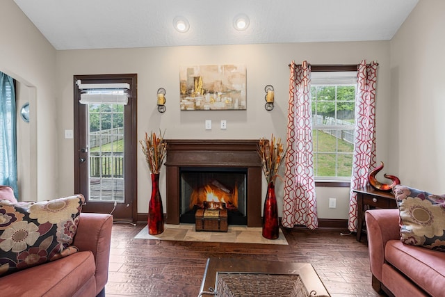 living area featuring baseboards, a fireplace with flush hearth, a healthy amount of sunlight, and hardwood / wood-style floors