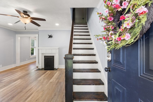 stairway with recessed lighting, wood finished floors, baseboards, a ceiling fan, and crown molding