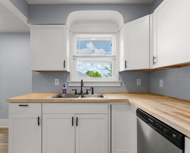 kitchen with stainless steel dishwasher, a sink, white cabinets, and butcher block counters