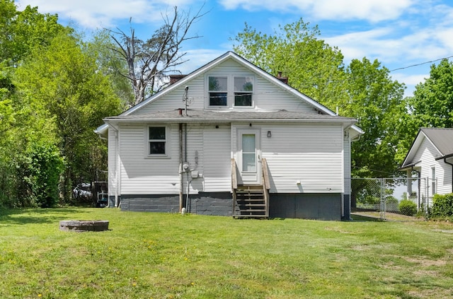rear view of house featuring a chimney, a yard, a fire pit, fence, and entry steps