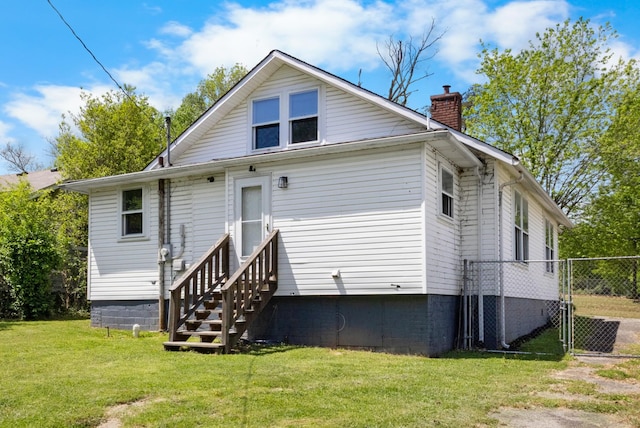 rear view of house featuring a lawn, crawl space, entry steps, and a chimney