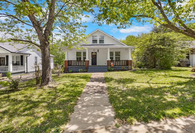 bungalow with a porch, a front yard, and brick siding