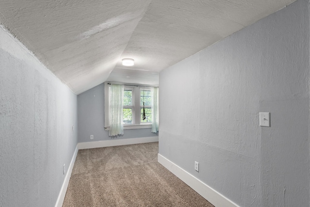 additional living space featuring lofted ceiling, a textured ceiling, baseboards, and carpet floors