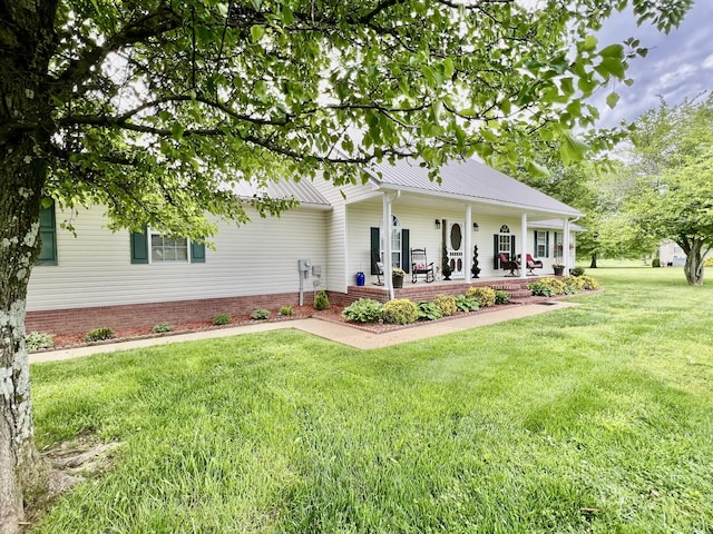 rear view of house with covered porch, metal roof, and a lawn