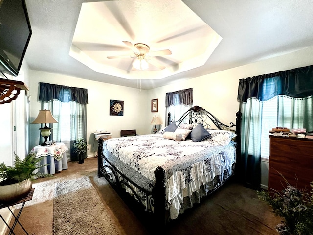 bedroom with baseboards, a raised ceiling, a ceiling fan, and carpet